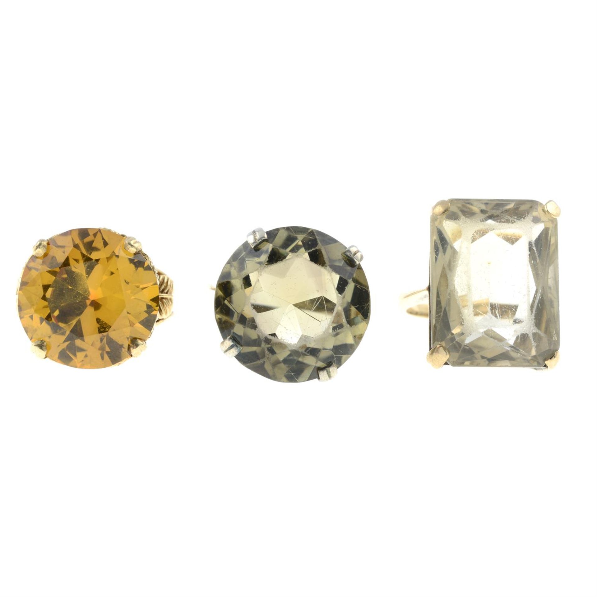 Three citrine, smokey quartz and synthetic yellow sapphire single-stone rings.