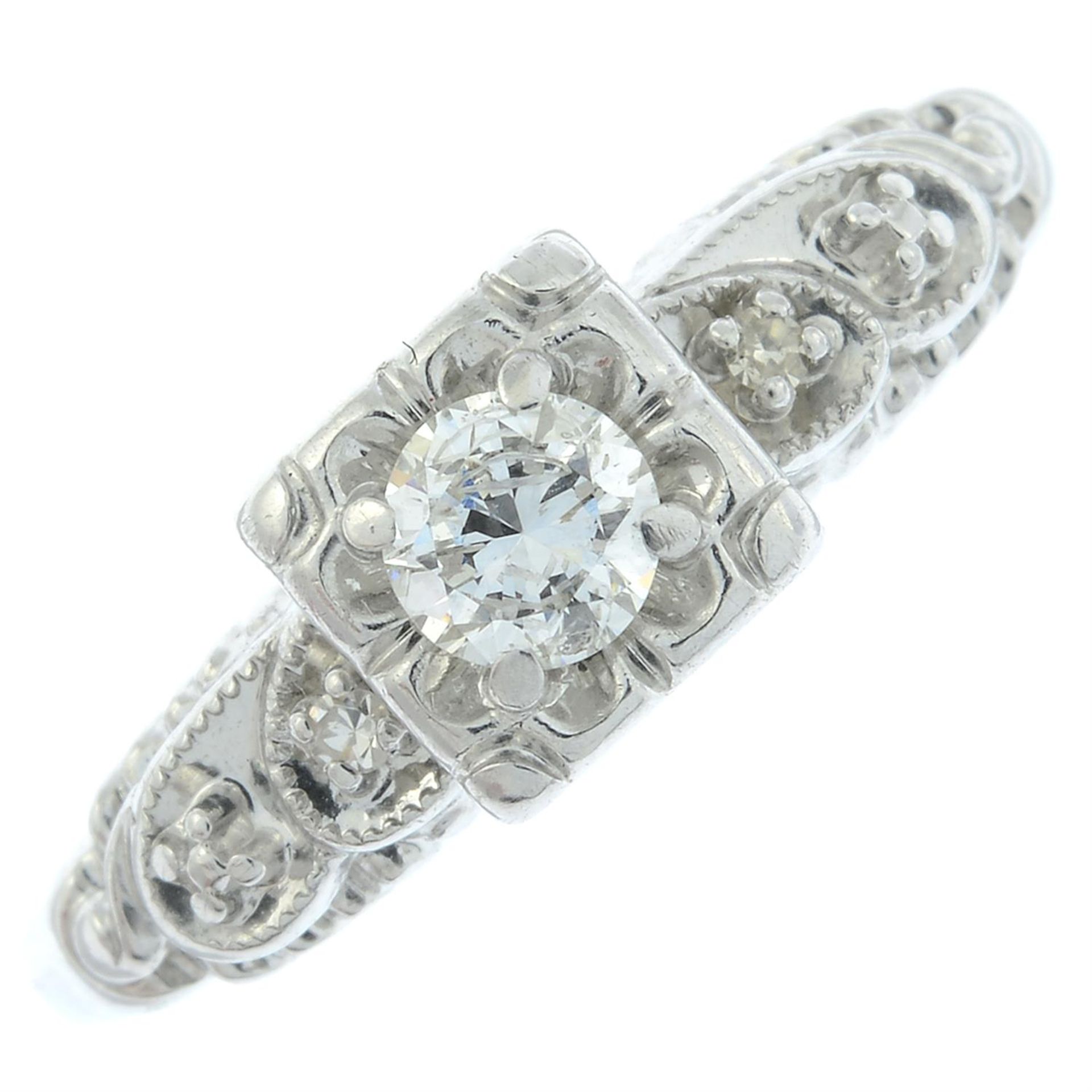 A brilliant-cut diamond single-stone ring, with diamond shoulders.