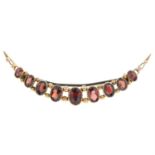 An early 20th century 9ct gold garnet crescent brooch.