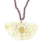 A bowenite pendant, carved as a moth, suspended from a garnet bead necklace.