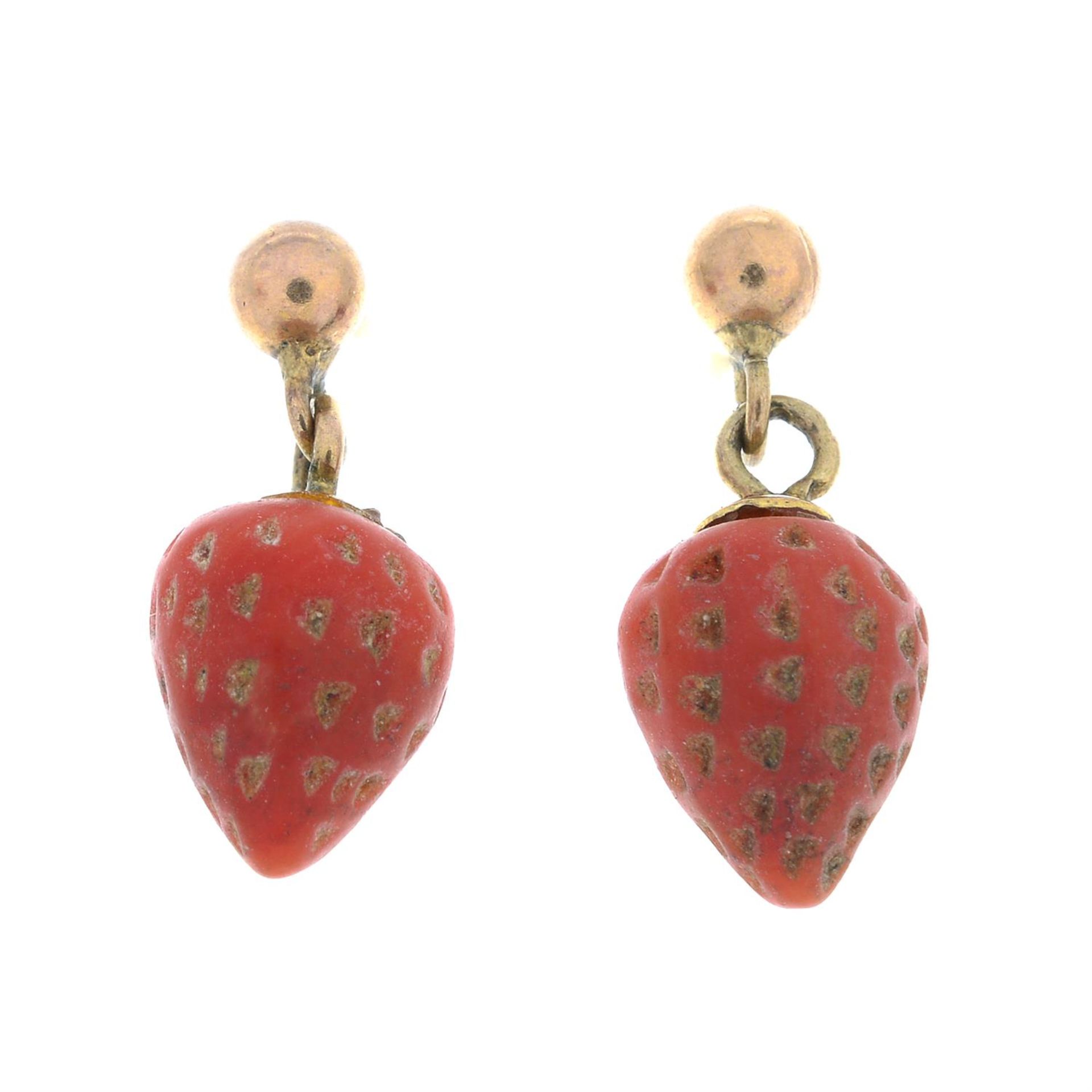 A pair of coral drop earrings, each carved to depict a strawberry.