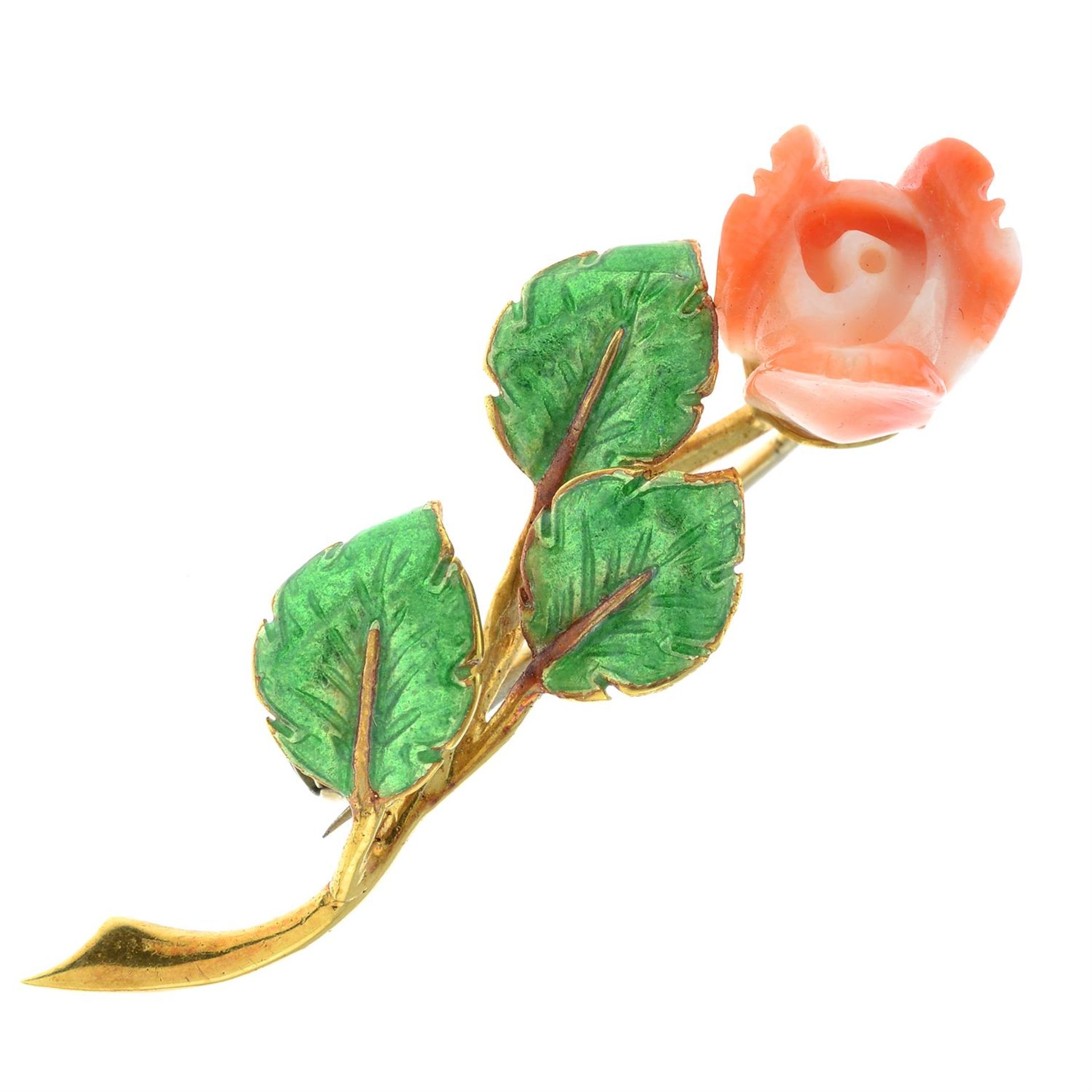 A carved coral rose brooch, with green enamel leaves.