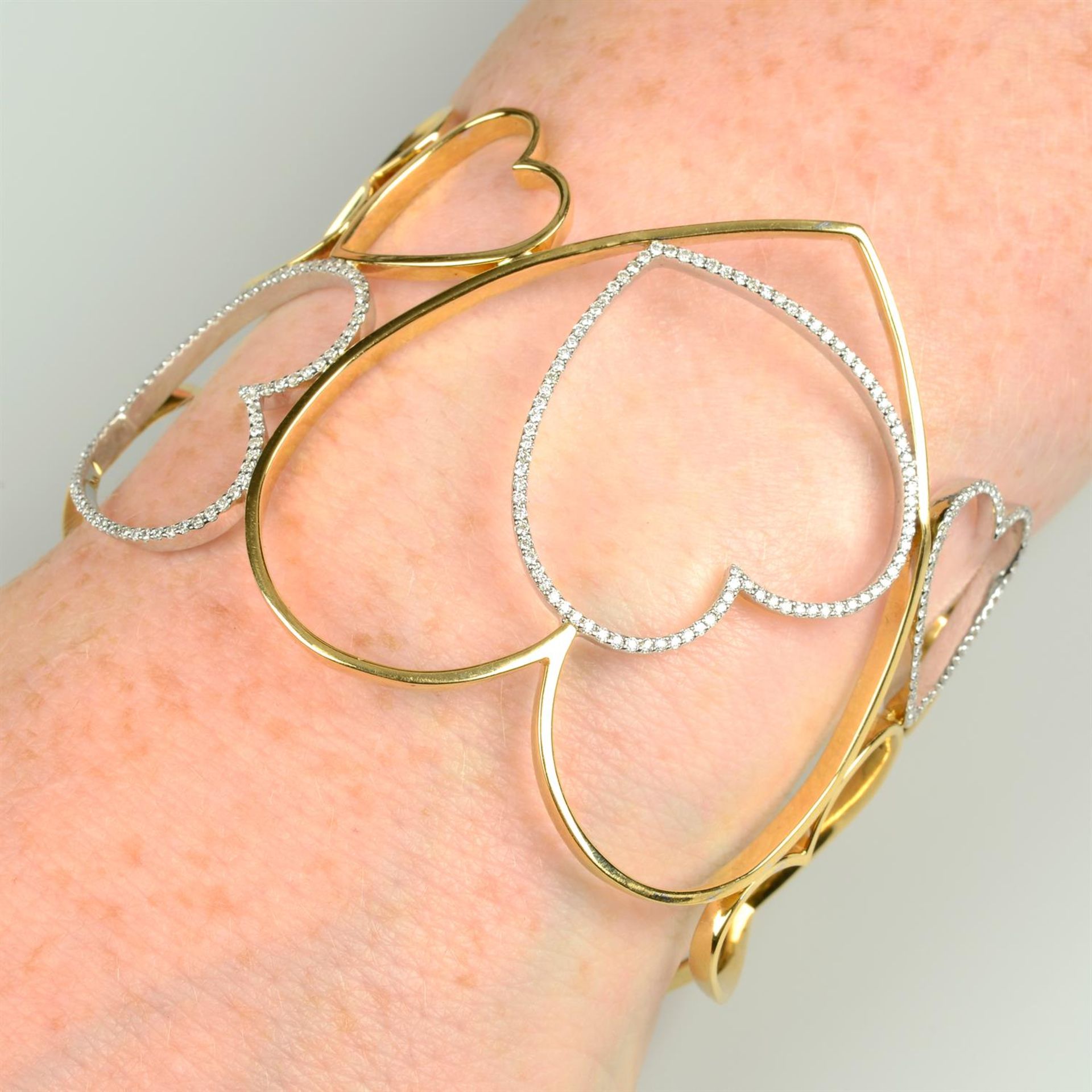 An openwork heart motif bangle, with diamond highlights.