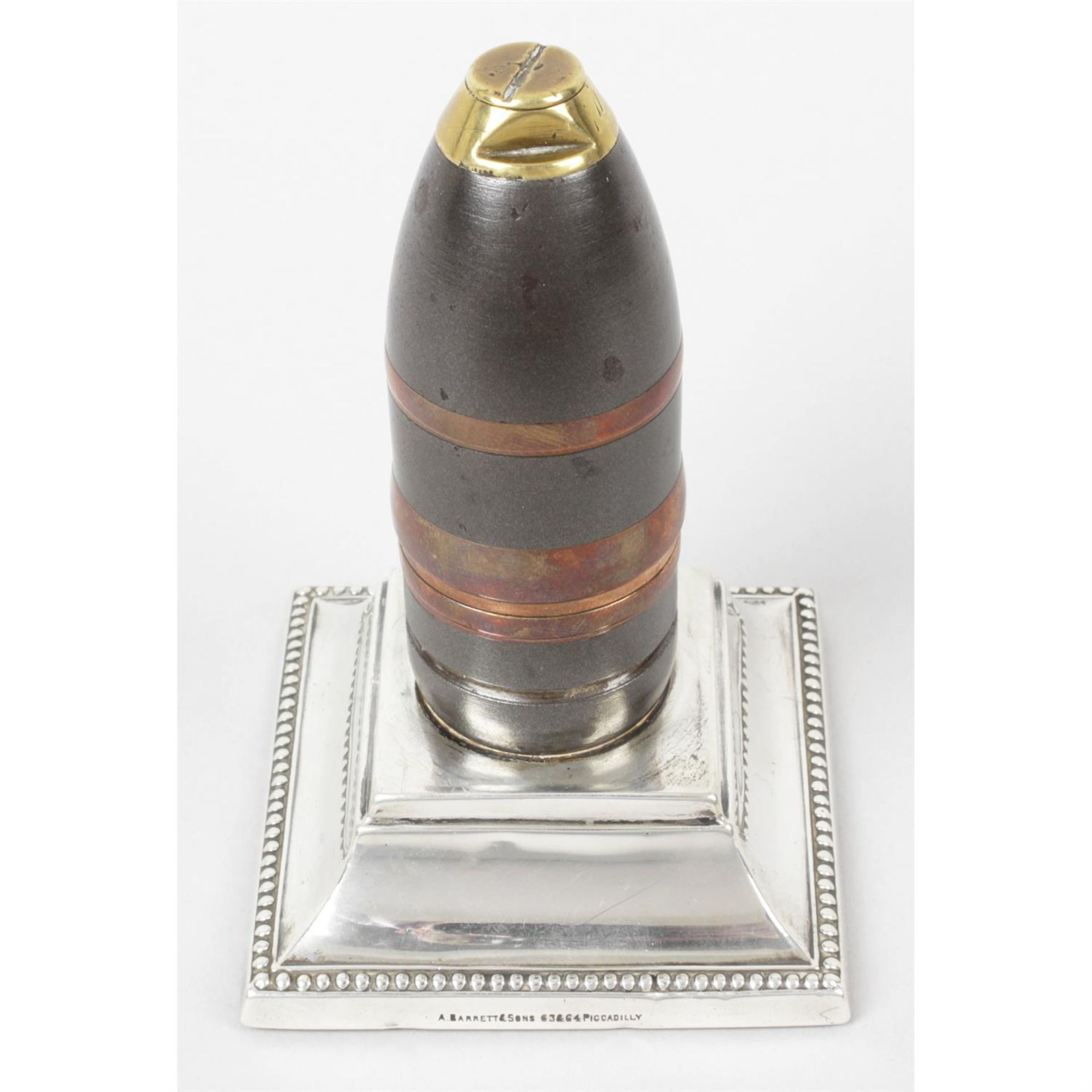 A bullet shell mounted on a filled silver base.