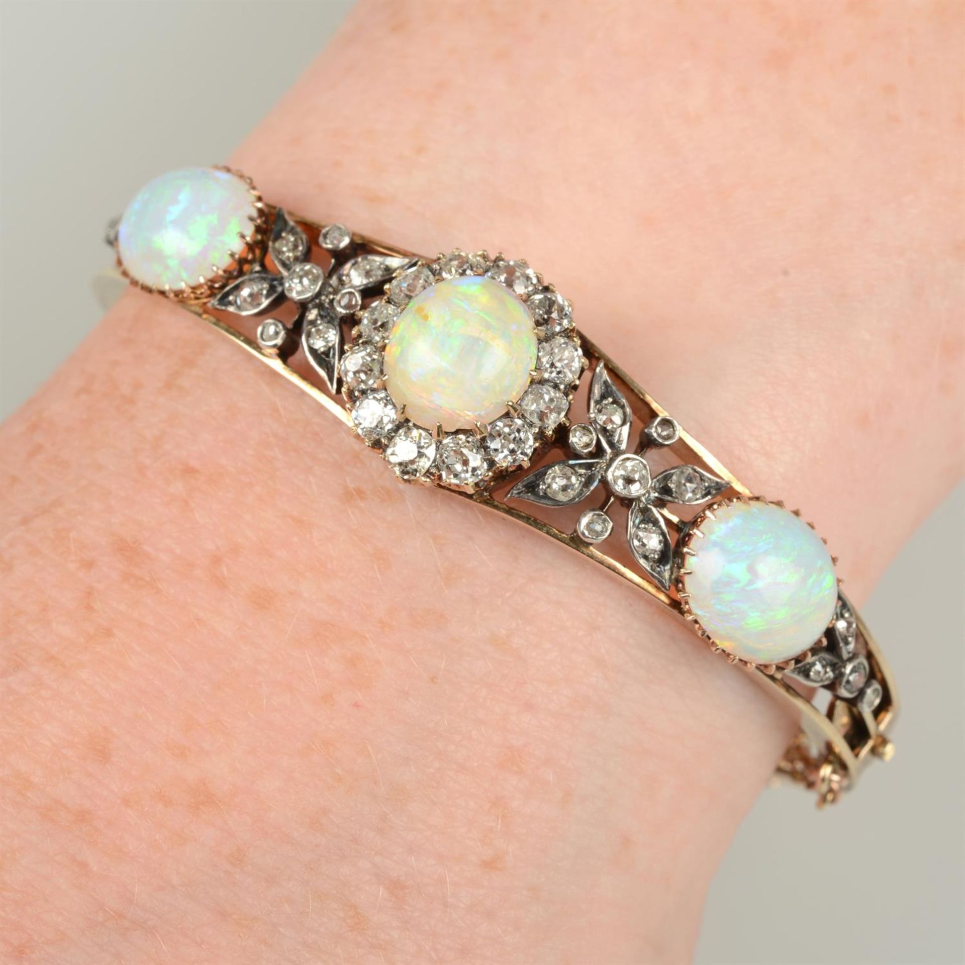 A late 19th century silver and gold opal and old-cut diamond floral cluster hinged bangle.