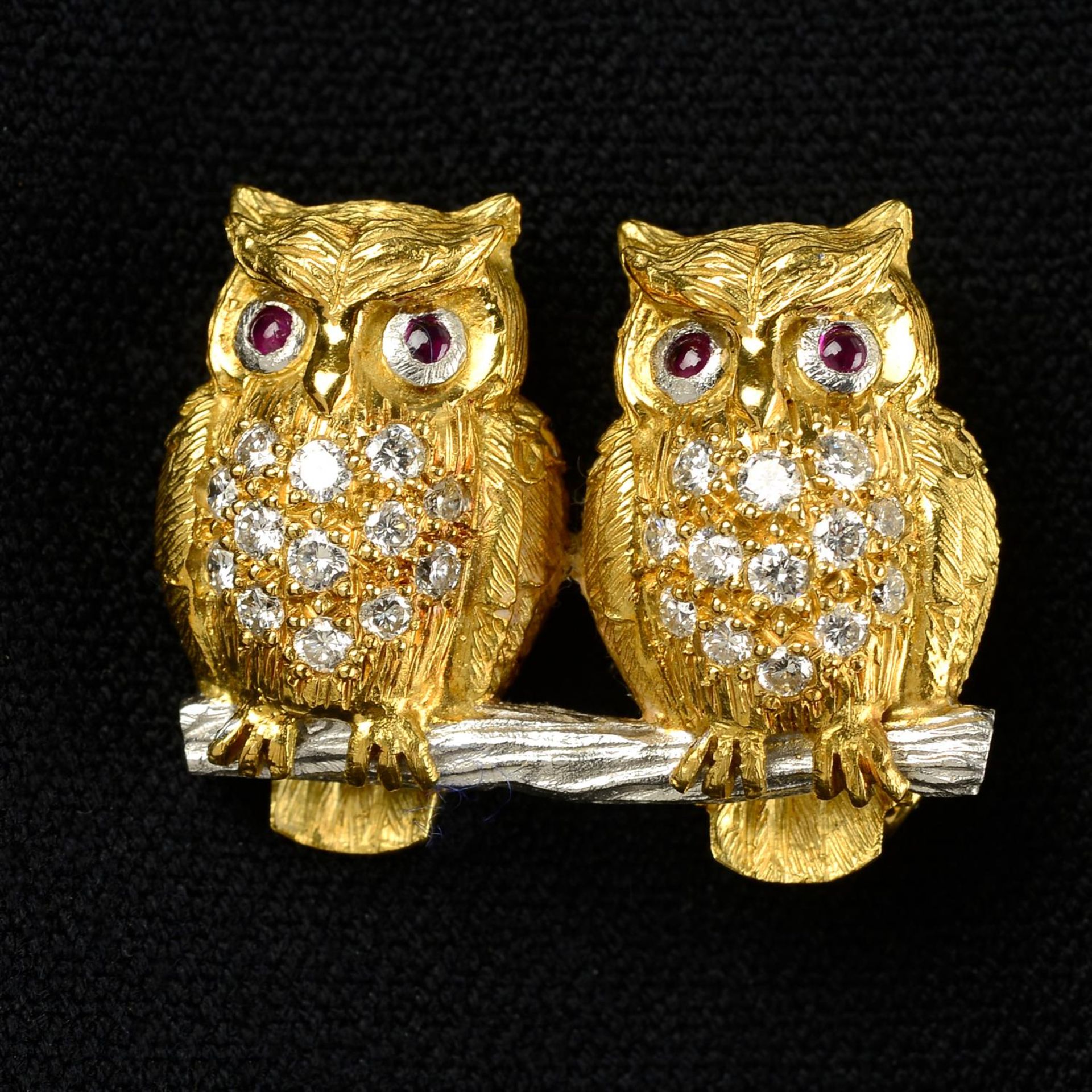 A bi-colour 18ct gold brilliant-cut diamond brooch, depicting a pair of owls, with ruby eyes, by E.