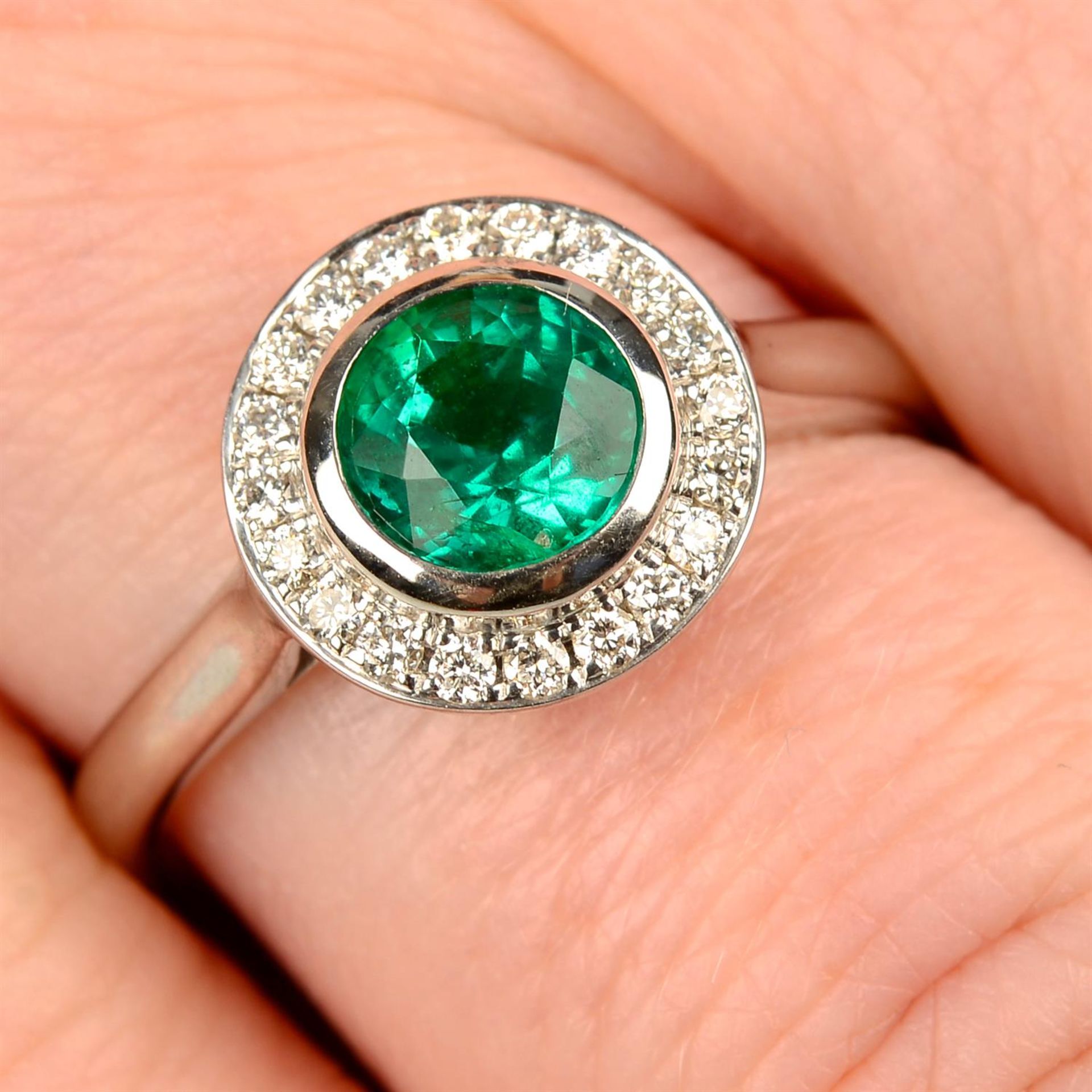 An emerald and brilliant-cut diamond cluster ring.