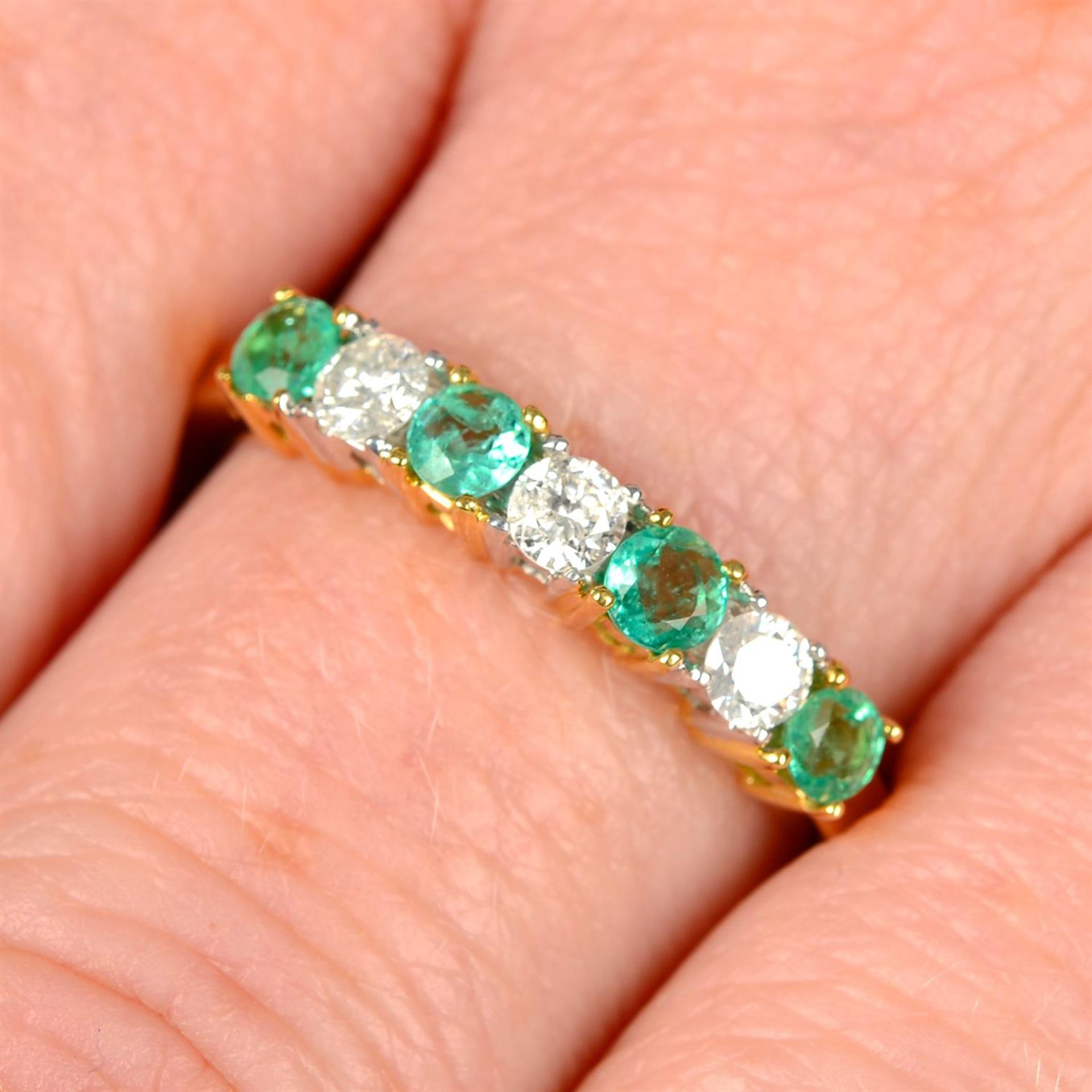 An 18ct gold alternating emerald and brilliant-cut diamond line ring.