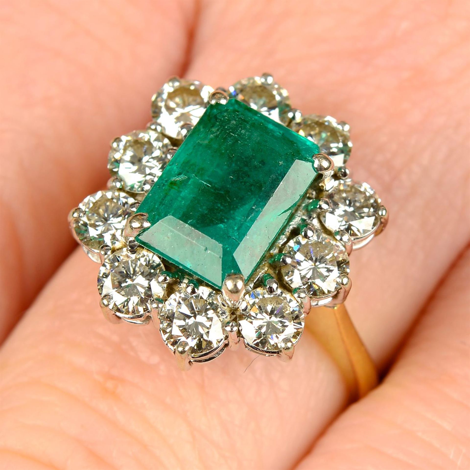 An 18ct gold emerald and brilliant-cut diamond cluster ring.