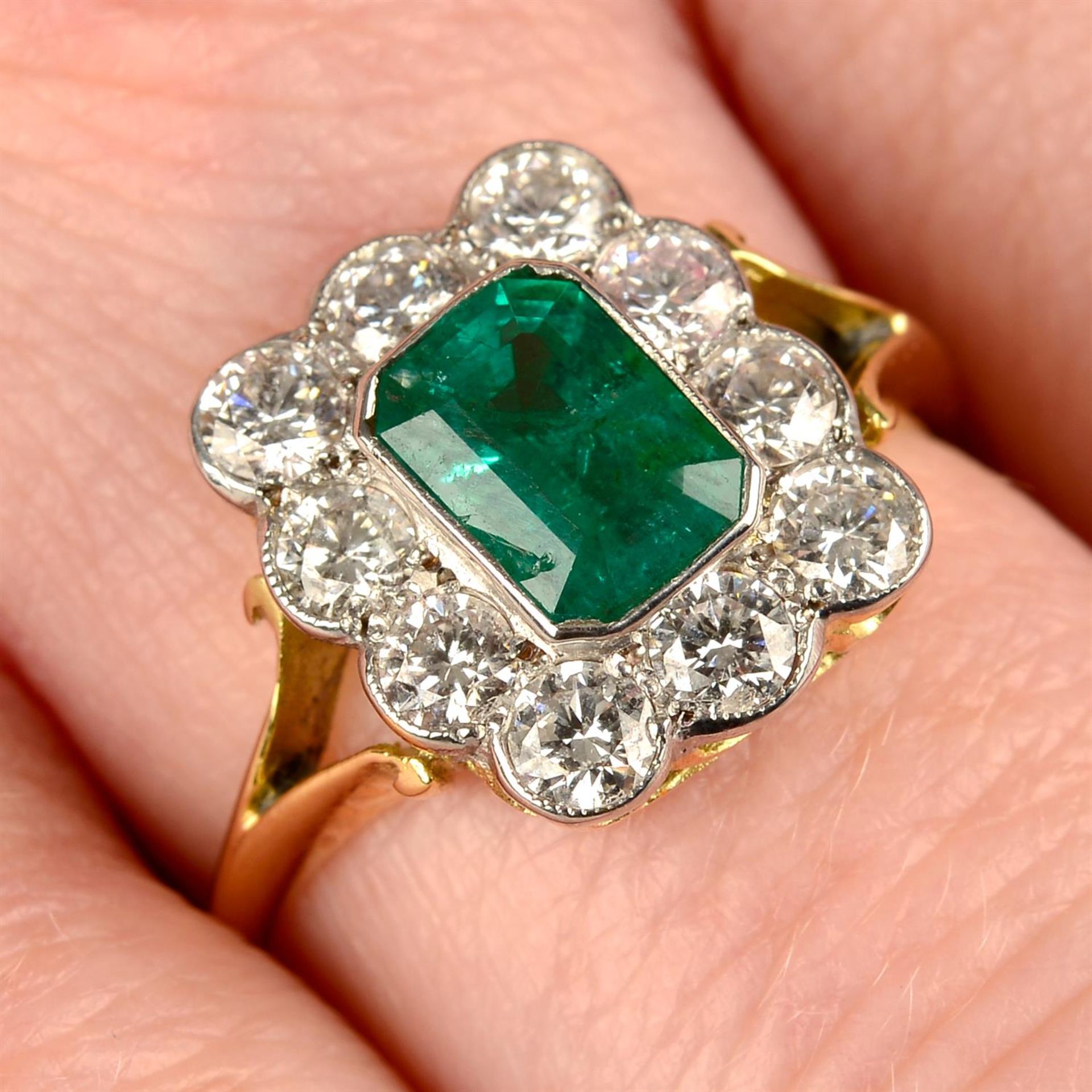 An emerald and brilliant-cut diamond cluster ring.