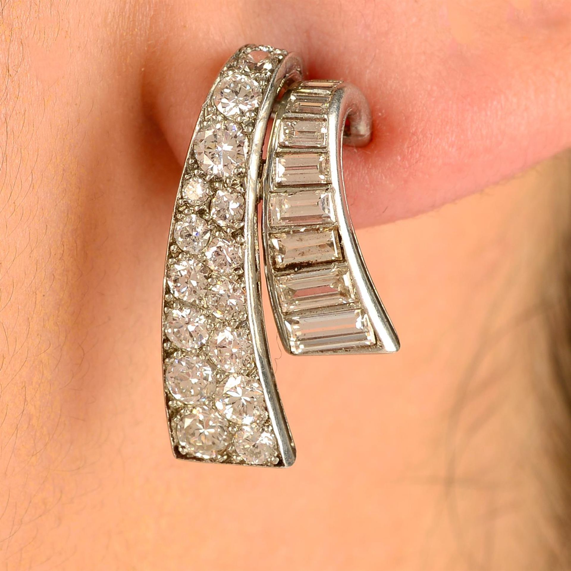 A pair of mid 20th century platinum baguette and brilliant-cut diamond scroll earrings.