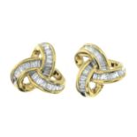 A pair of baguette-cut diamond knot earrings.