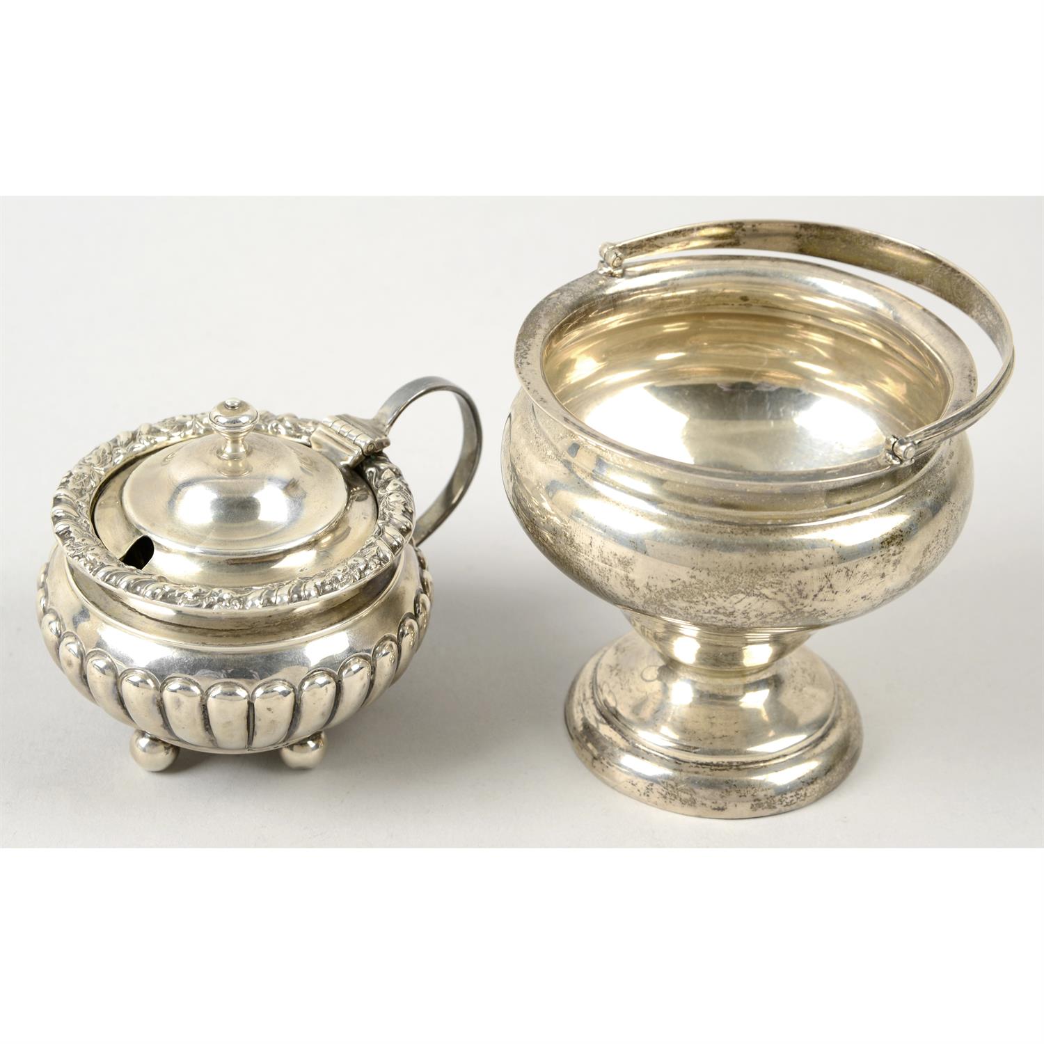 An Edwardian silver mustard pot, and a swing handle pedestal sugar bowl. (2).