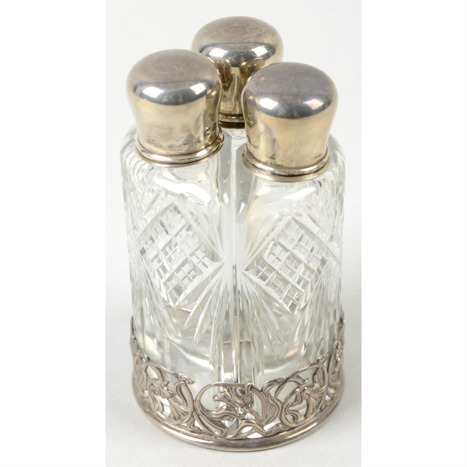 An Edwardian silver mounted three bottle perfume set.