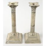 A pair of George V silver Corinthian column candlesticks (loaded).
