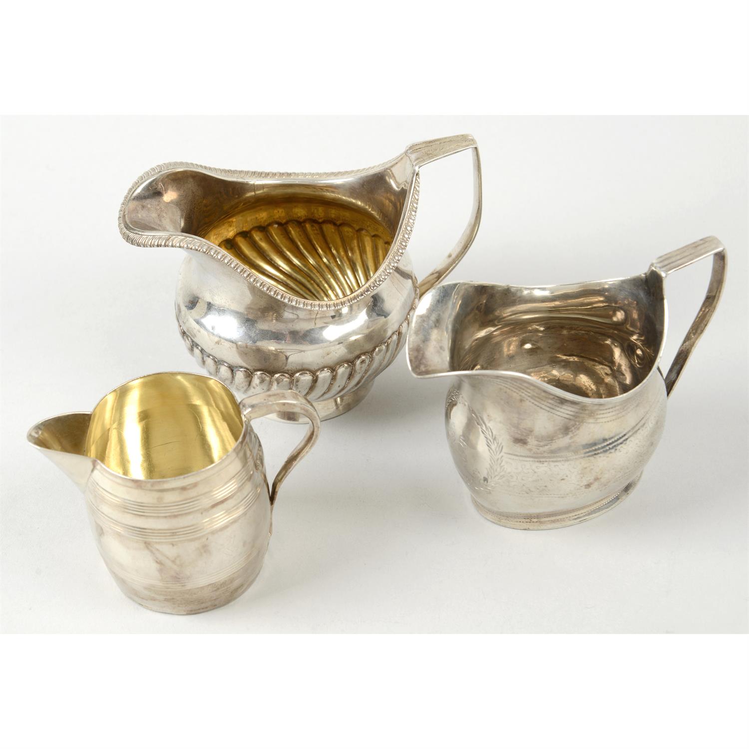 Three George III silver cream jugs (some damage/repairs). (3).