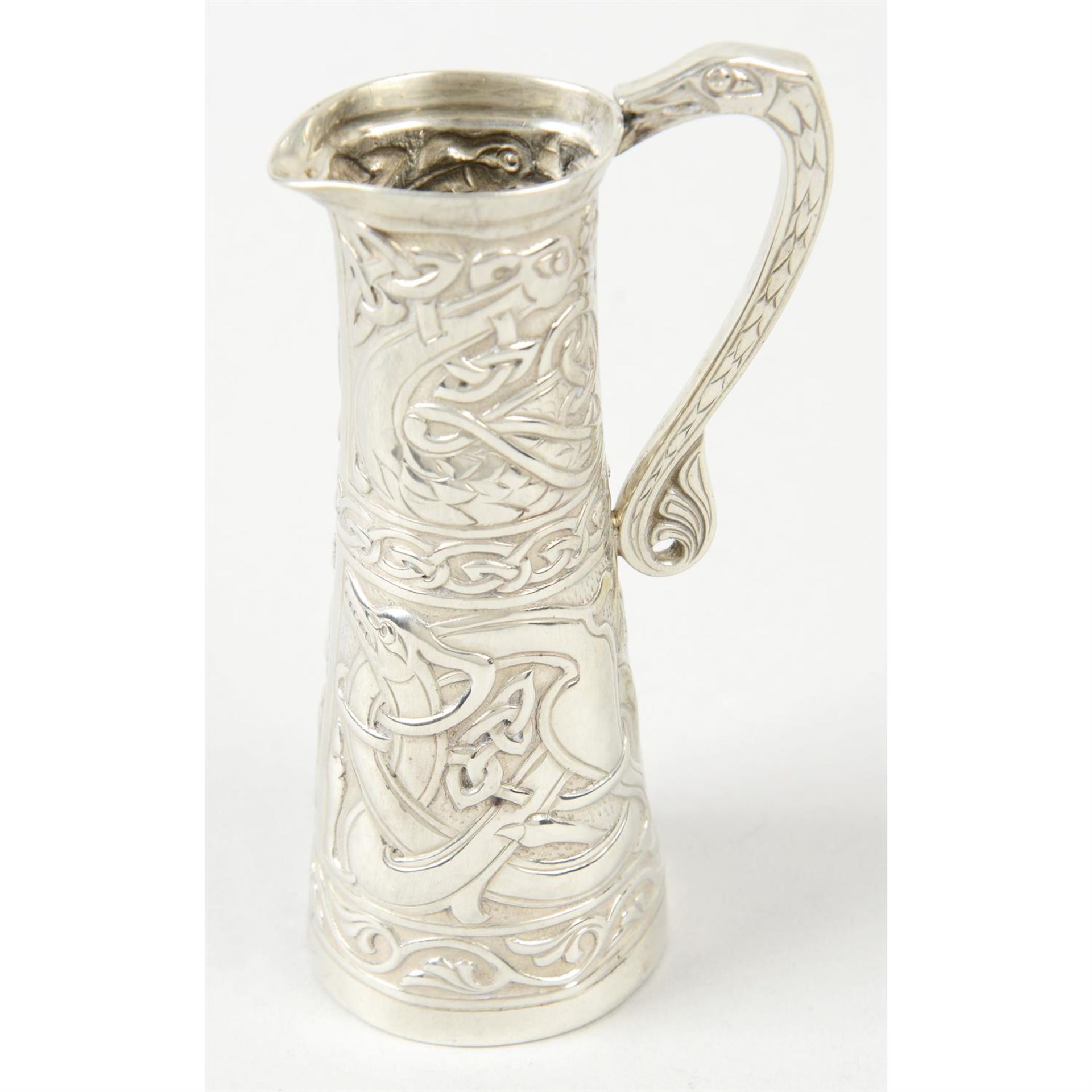 An Edwardian silver cream jug with Celtic motif decoration.