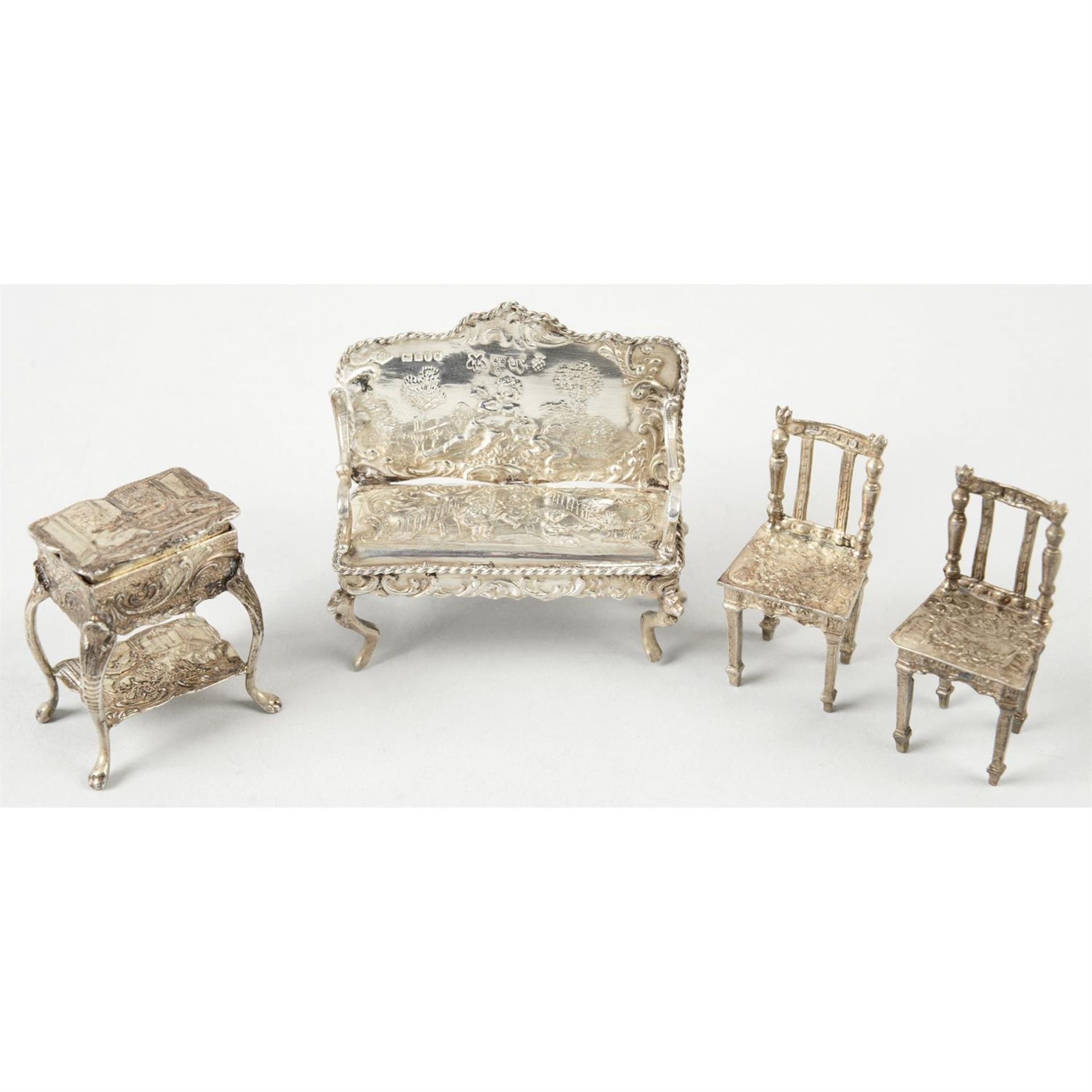 A collection of silver miniature or toy furniture to include a settee, two chairs & a cabinet table,