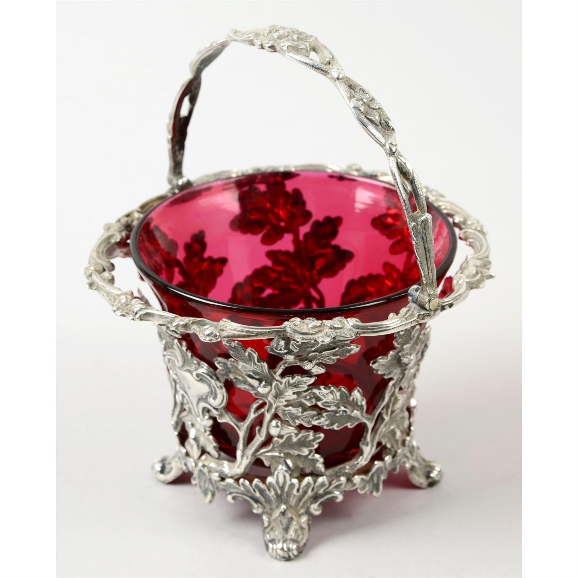 A Victorian pierced silver sugar basket with cranberry glass liner.
