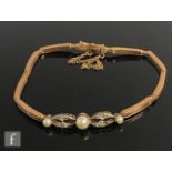 An early 20th Century 9ct rose gold three bar gate bracelet detailed with three cultured pearls