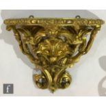 A late 19th Century gilt painted pine and gesso wall bracket, the cartouche shaped plateau above