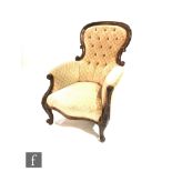 A Victorian mahogany framed easy chair upholstered in a pale tan fan design, on cabriole legs to the