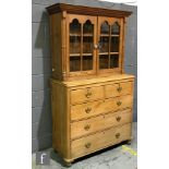 A late 19th to early 20th Century pine double door display case, with cornice pediment above a chest