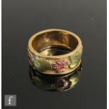 An unmarked two coloured yellow metal ring detailed with four rubies to a stylised flower head
