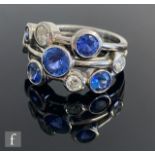 A 18ct hallmarked white gold Boodles style tanzanite and diamond ring, nine collar set stones to the