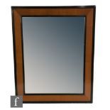 An early 20th Century wall mirror of rectangular form, the maple veneered frame with black painted