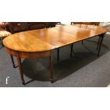 A George IV mahogany D-end dining table with cross-banded and line inlaid borders, complete with a