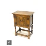 A 20th Century oak pot cupboard with carved double doors, above a turned stretcher frame, height