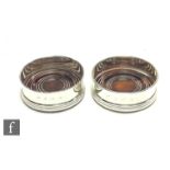 A pair of modern hallmarked silver circular bottle coasters, silver mounted turned wooden bases,