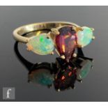 A 9ct hallmarked opal and rhodolite three stone ring, central rhodolite flanked by pear shaped
