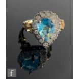 A 9ct blue topaz and diamond cluster ring, central pear shaped claw set topaz, length 8.5mm,