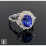 An 18ct white gold tanzanite and diamond cluster ring, central oval tanzanite weight 3.00ct within a