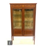 An Edwardian satinwood crossbanded and inlaid display cabinet enclosed by a pair of doors below a