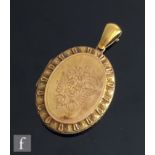 A late 19th Century 15ct oval locket with central foliate engraved decoration within panelled
