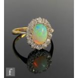 An early 20th Century opal and diamond cluster ring, central oval opal length 10mm, within a