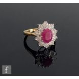 An 18ct hallmarked ruby and diamond cluster ring, central oval ruby weight 2.25ct, within a ten
