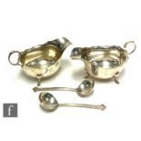 A pair of hallmarked silver sauce boats of plain form terminating in flying scroll handles and