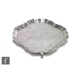 A hallmarked silver cushioned square card waiter with part foliate engraved decoration within