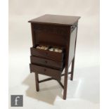 A small Edwardian mahogany sewing cabinet, the lift up top over three drawers, on champhered legs