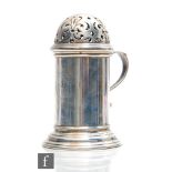 A hallmarked silver castor of plain cylindrical form, with pierced domed top and plain scroll side