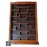 A Chinese hardwood snuff bottle cabinet, the glazed front cabinet with hinged door revealing a