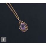 An Edwardian style 9ct hallmarked single stone amethyst pendant, oval claw set stone to a scroll