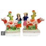 A mirrored pair of Staffordshire spill vases modelled as facing cows with a lady and gentleman stood