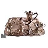 A hallmarked silver four piece pedestal tea set of facetted panel form below castellated borders,