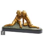 An early 20th Century gilded spelter study, modelled as two seated children sharing a secret on a