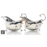 A pair of hallmarked silver sauce boats of plain panelled form terminating in pointed pad feet and